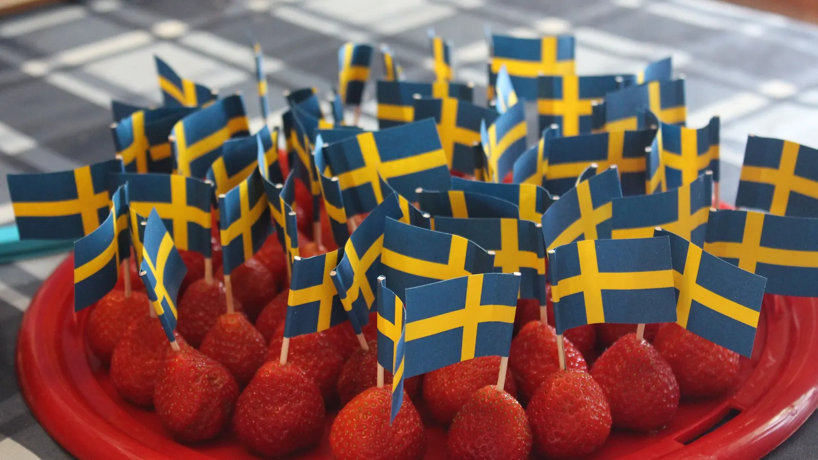 Jordgubbar med små svenska pappersflaggor på ett midsommarbord