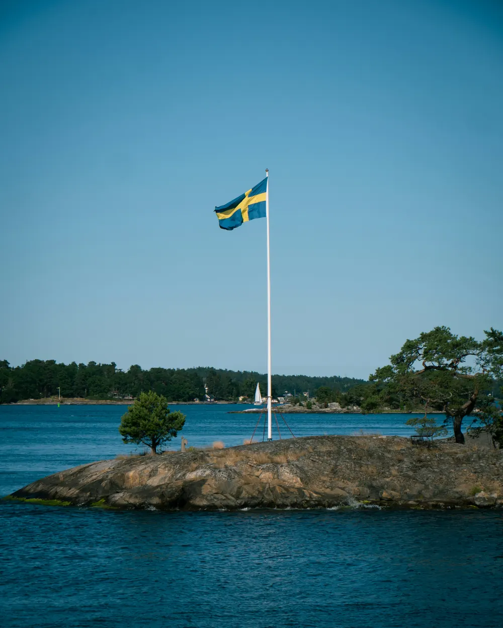 Flaggstång med svensk flagga på en liten klippö en sommardag