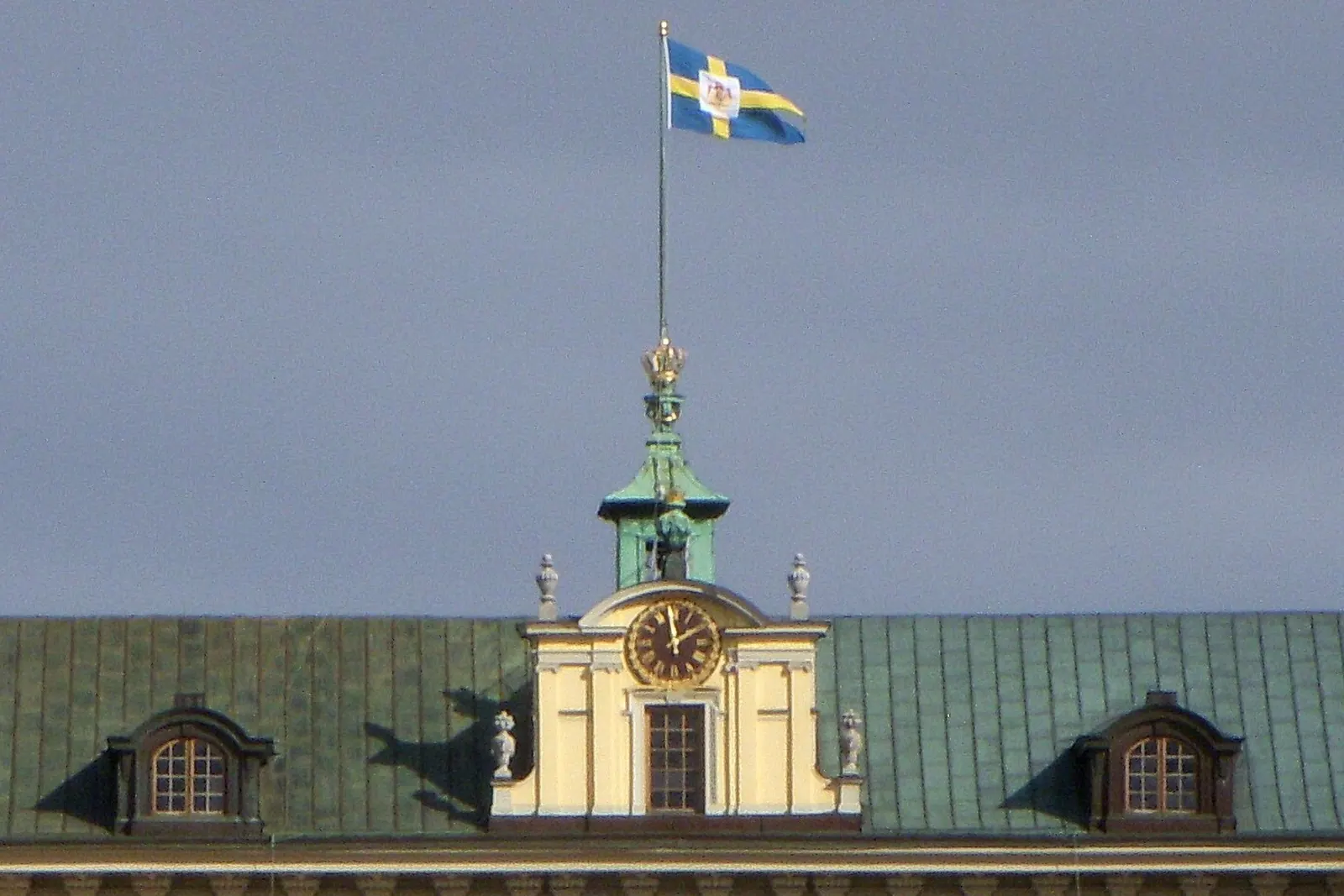 Tretungad flagga med riksvapnet på taket till Drottningholms slott