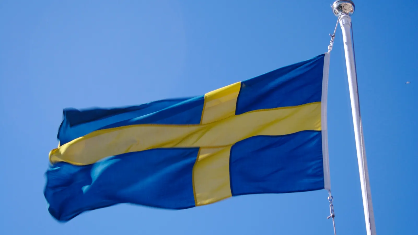 Svensk flagga som vajar i vinden vid toppen av en flaggstång