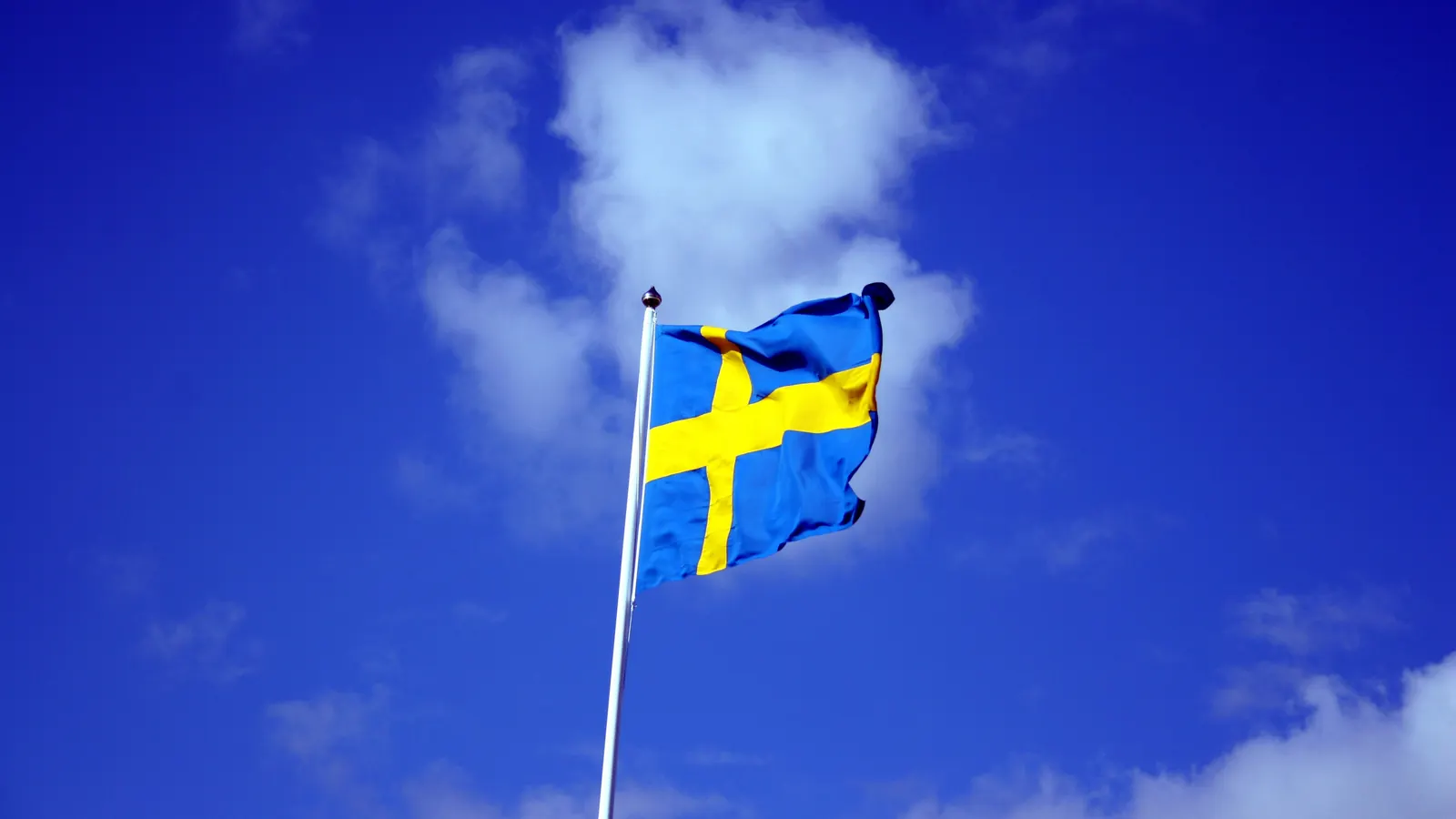 Svensk flagga på en flaggstång mot blå himmel