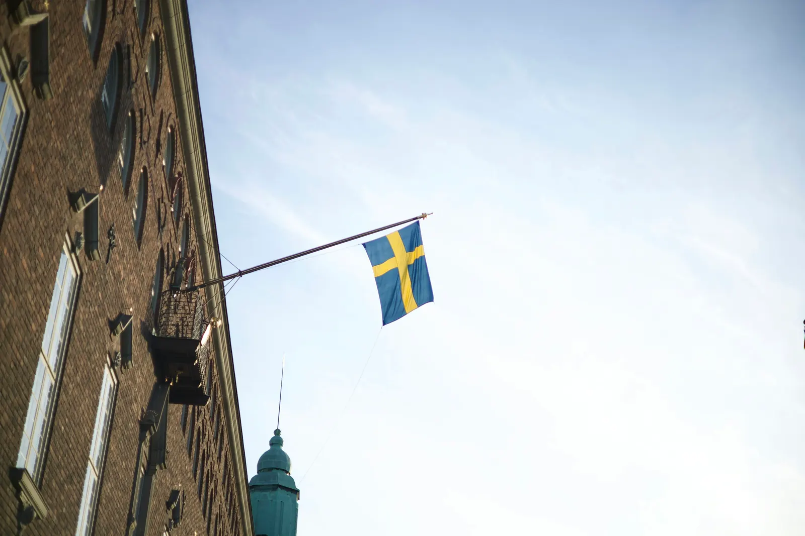 Svensk flagga på en snedställd fasadstång på en tegelbyggnad