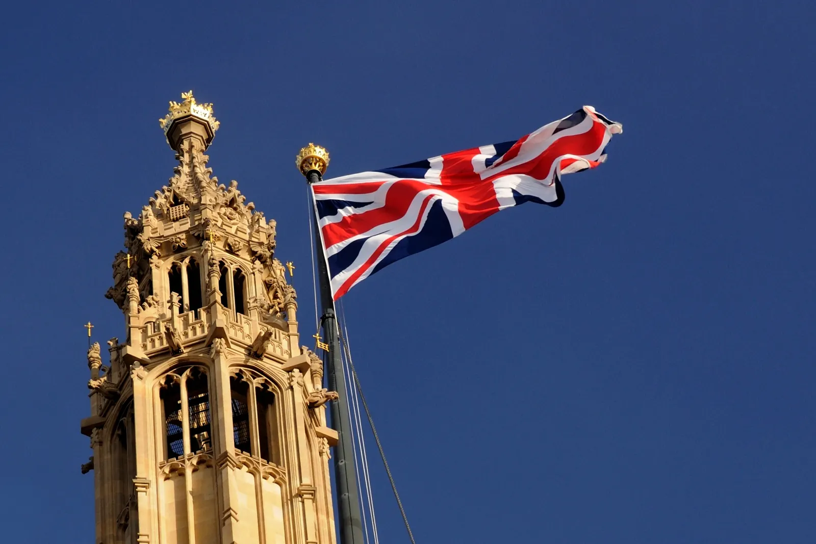 The Union Flag on Victoria Tower of the Palace of Westminster against a deep blue sky