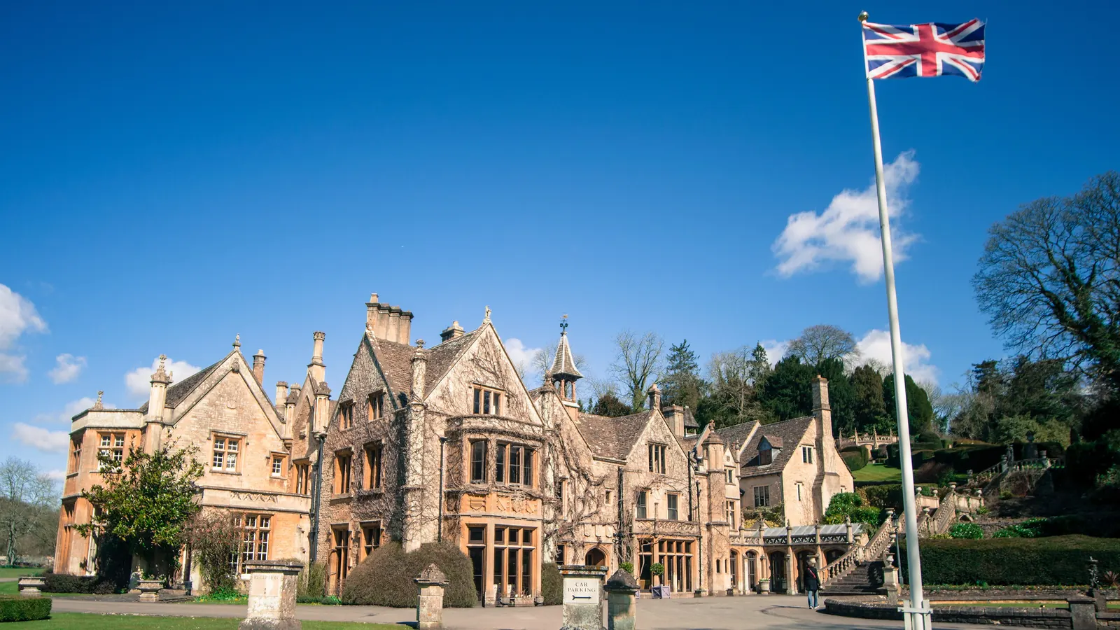 A tall flagpole with the Union Flag in front of the manor house at Castle Combe