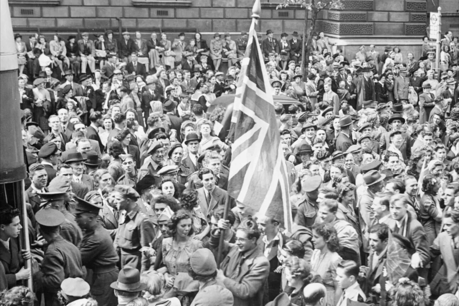 Crowds with a Union Flag celebrating VE Day in London on 8 May 1945