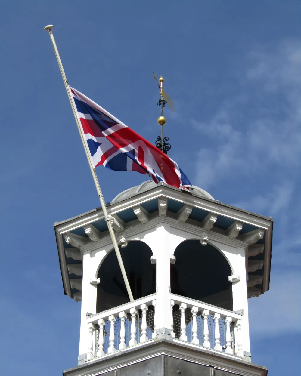 The Union Flag at half-mast on a white clock tower in Guildford