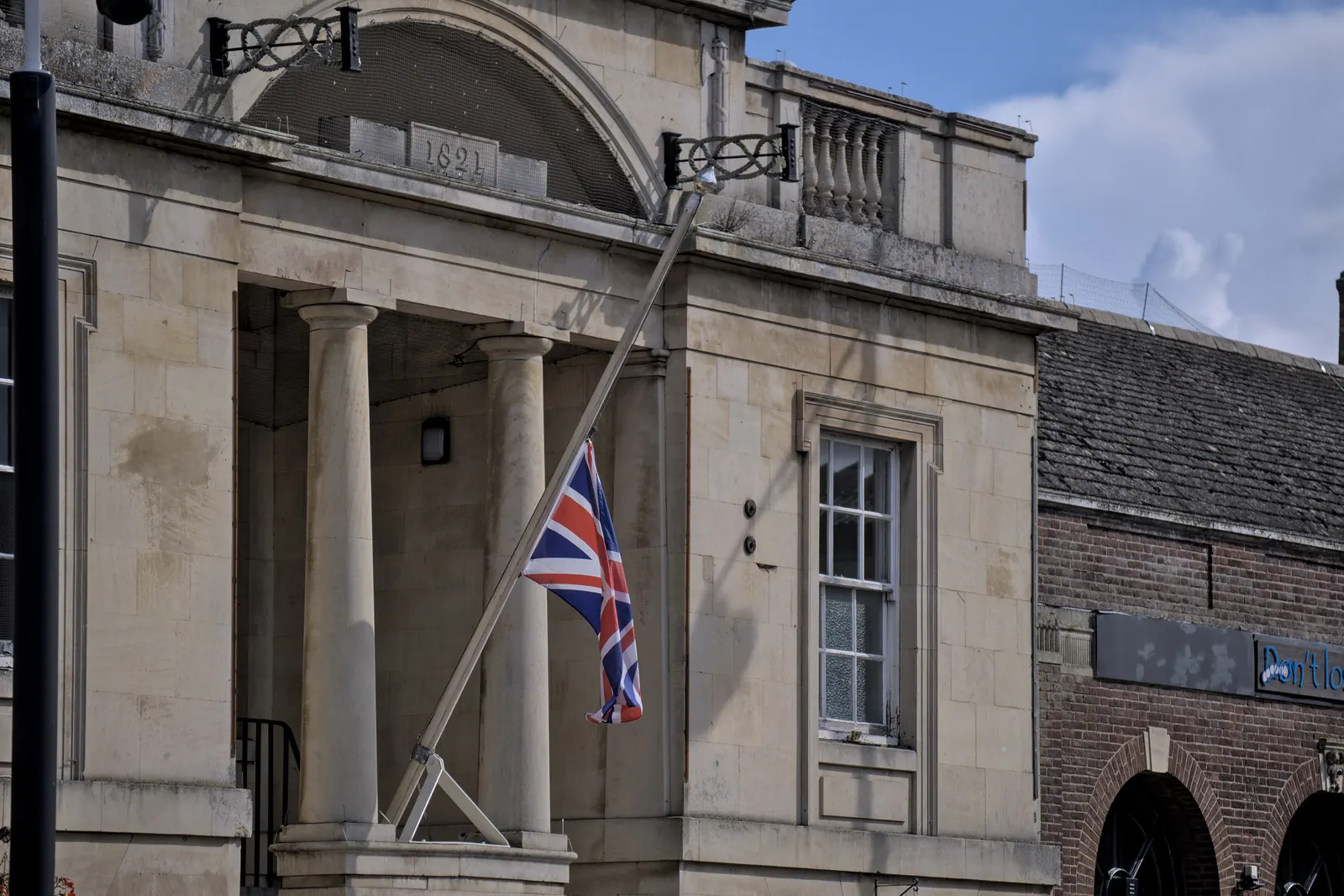 The Union Flag at half-mast on an angled flagpole on a building