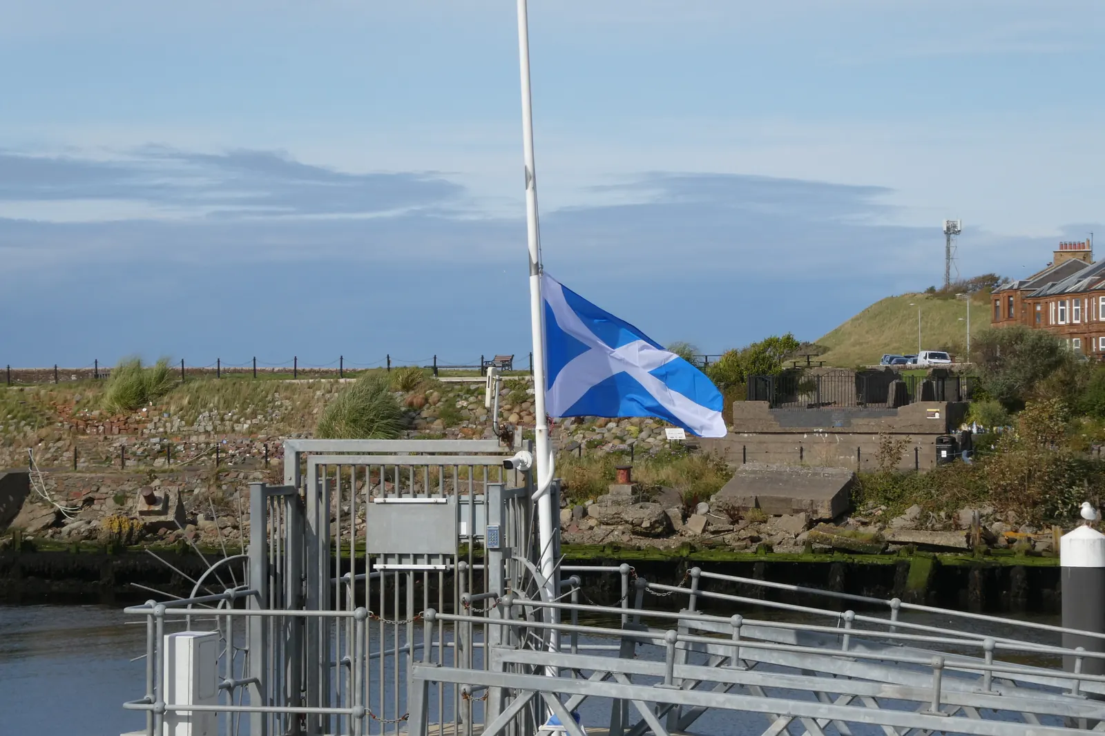 The Saltire at half-mast by a harbour in Scotland