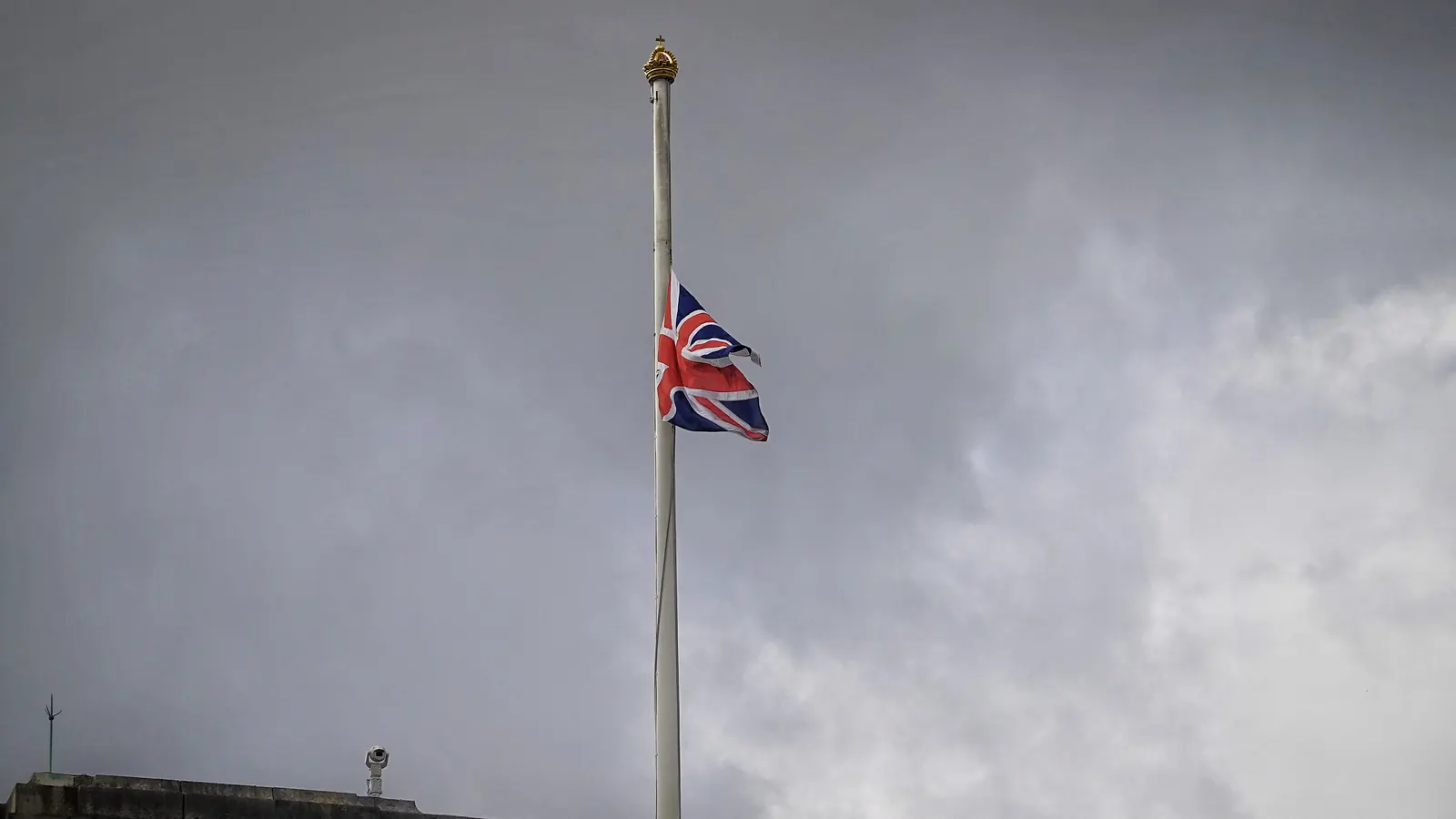 The Union Flag at half-mast against a grey sky