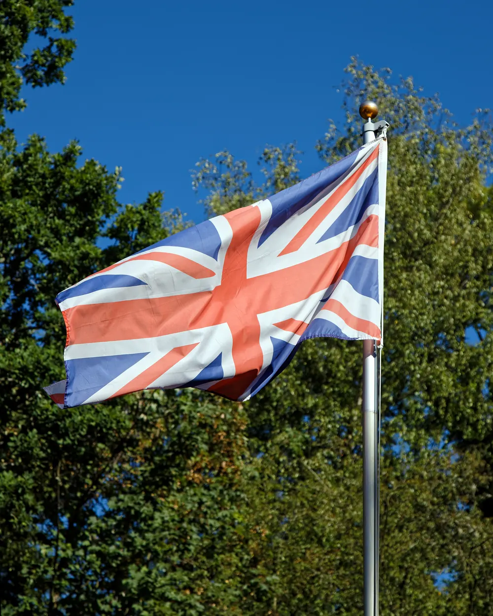 The Union Flag on a white flagpole between trees at Nuthurst, West Sussex
