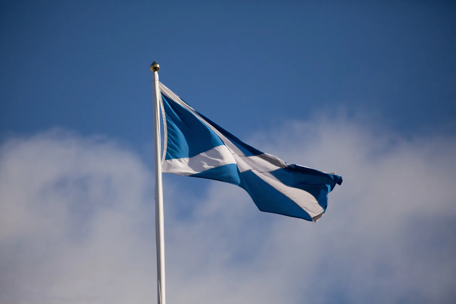 The white saltire of Scotland on a blue flag against the sky