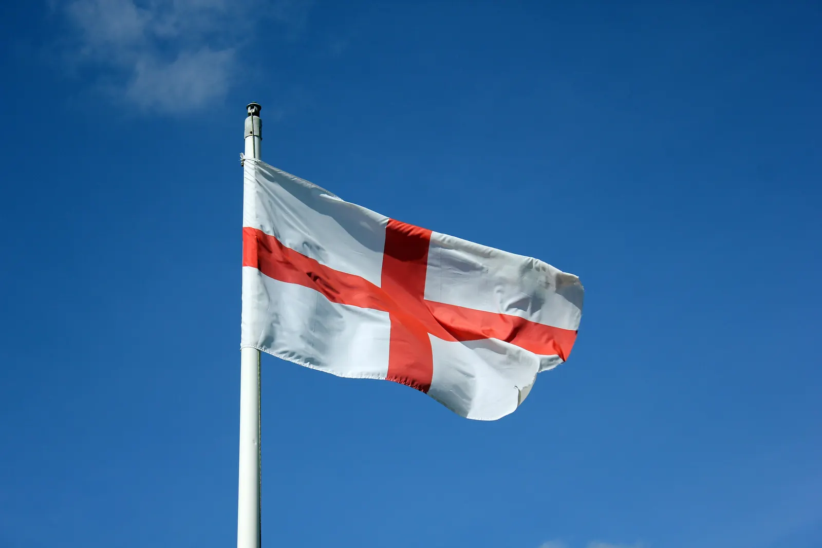 The red cross of St George on a white flag against a clear blue sky at Dutton Lock