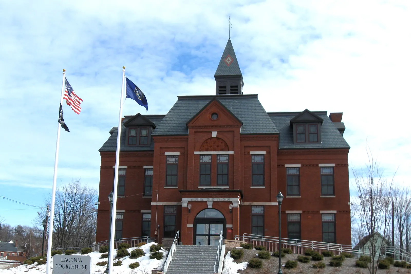 Laconia District Court in New Hampshire with the flag of the United States above the POW/MIA flag on one flagpole and the state flag on the other