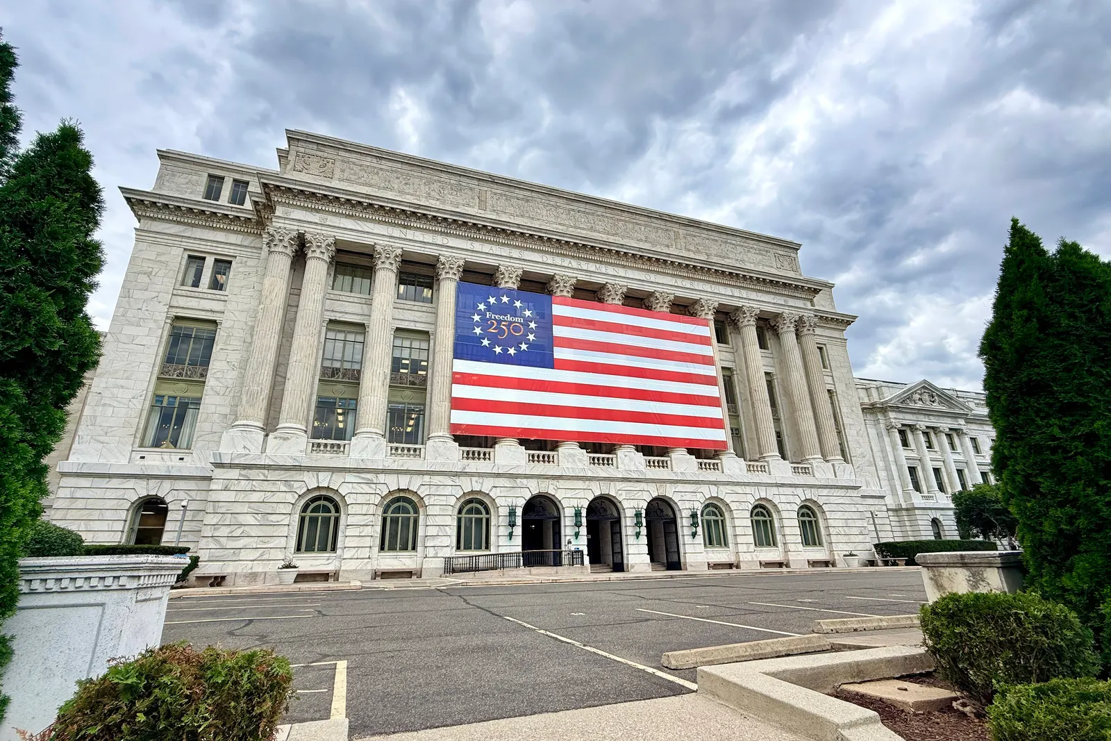 A large flag of the United States hung across the facade of a public building