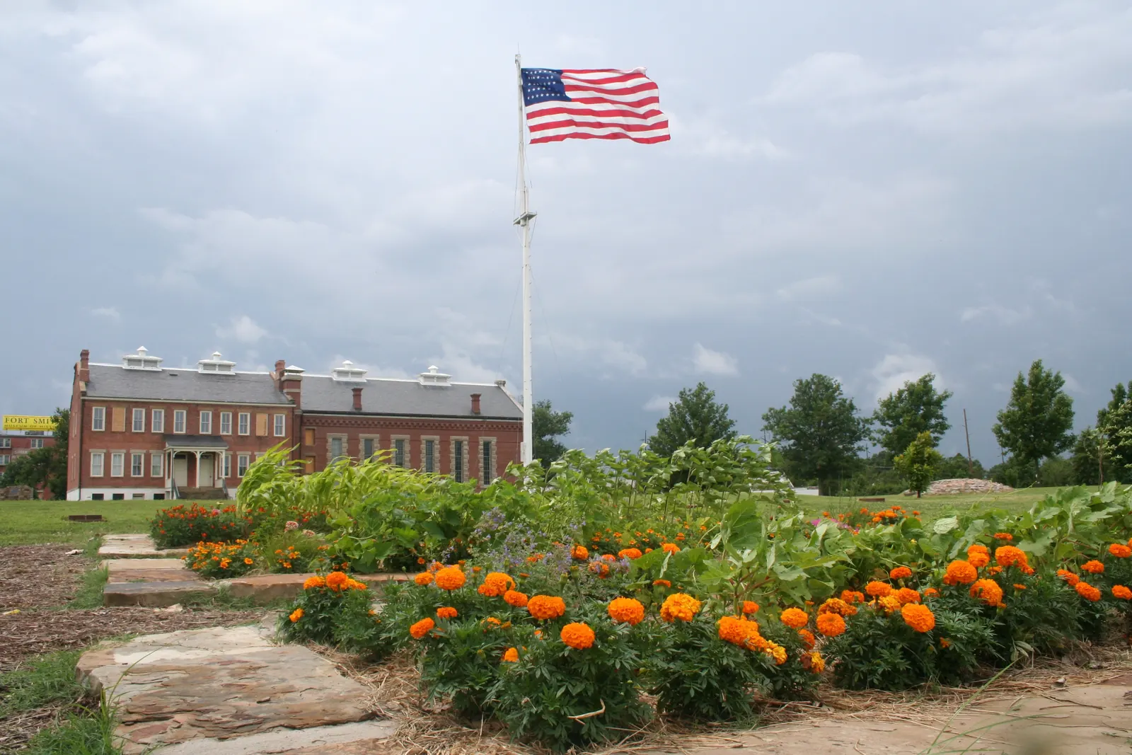 A large garrison flag on a tall flagpole beside a historic building