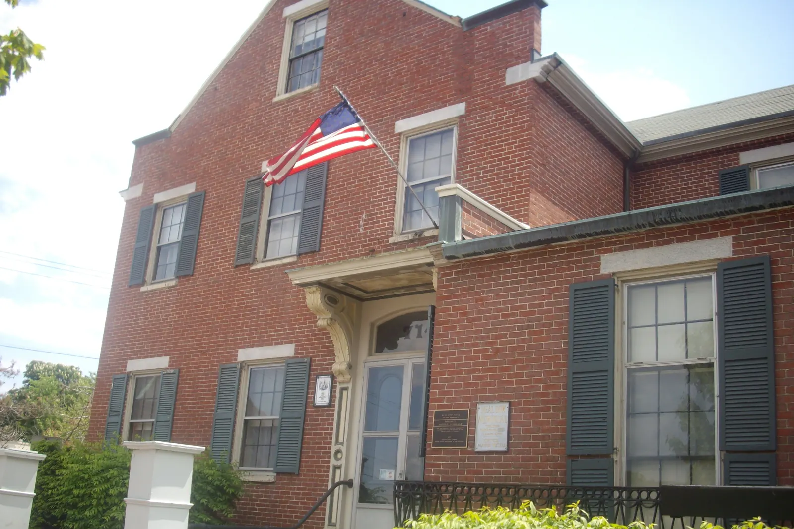 A brick house with the flag of the United States in a bracket by the front door